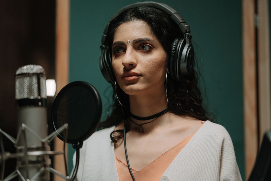 Female singer recording vocals in a professional music studio wearing headphones.