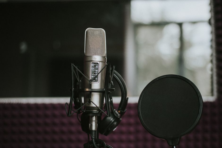 Close-up of a microphone with pop filter in a modern music studio environment.